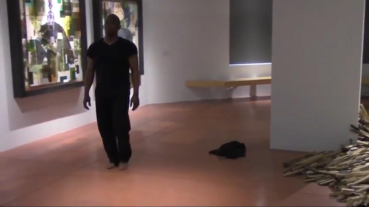 Boris Willis walking through the gallery beside a pile of branches