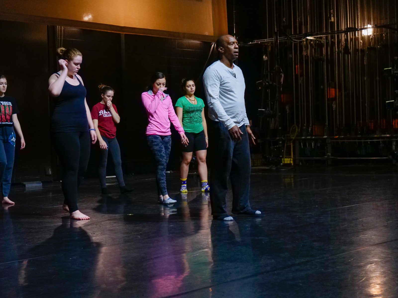 Boris Willis leading a line of dancers across a theater stage in rehearsal