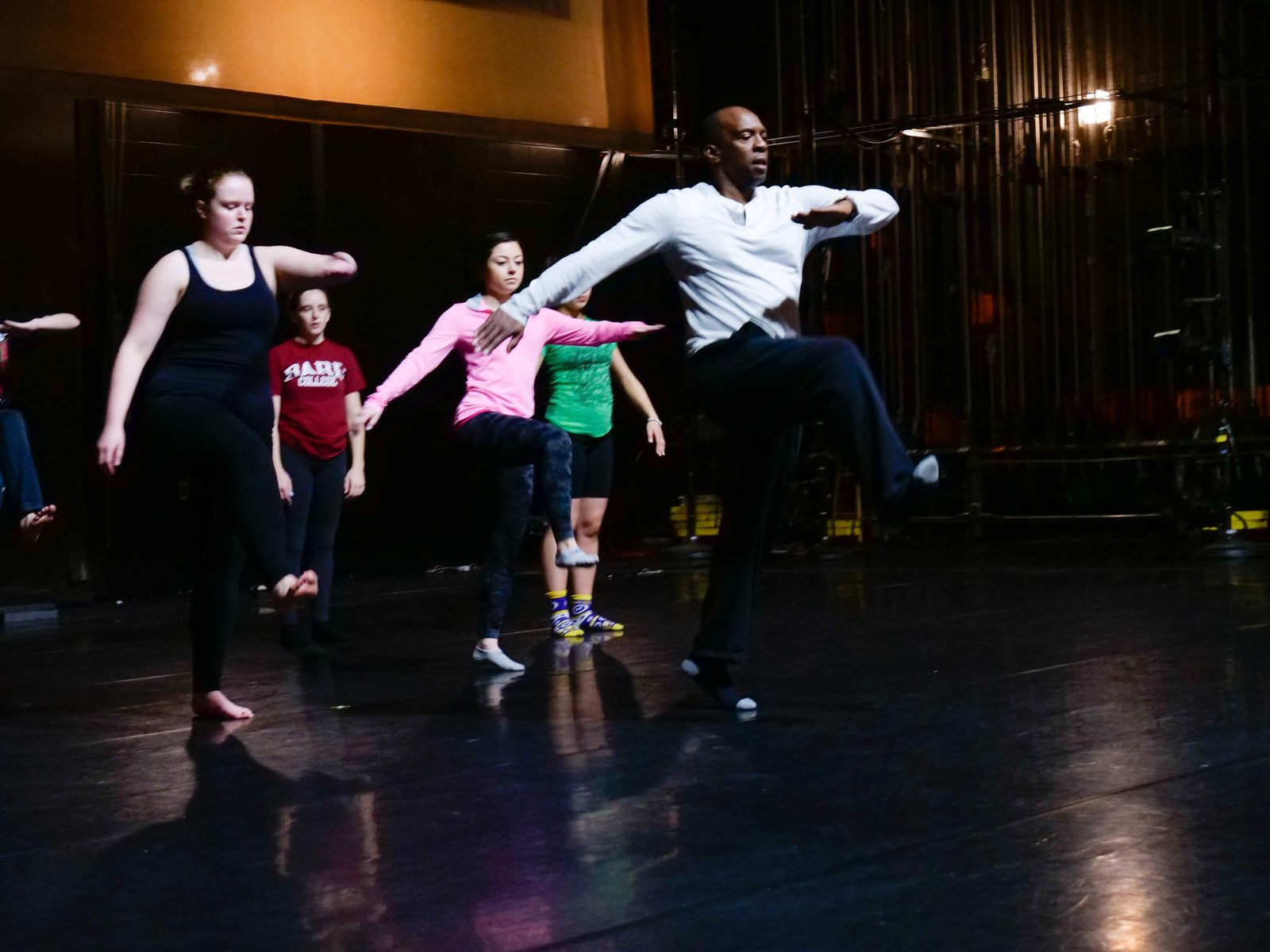 Boris Willis leaping with dancers in motion across the stage