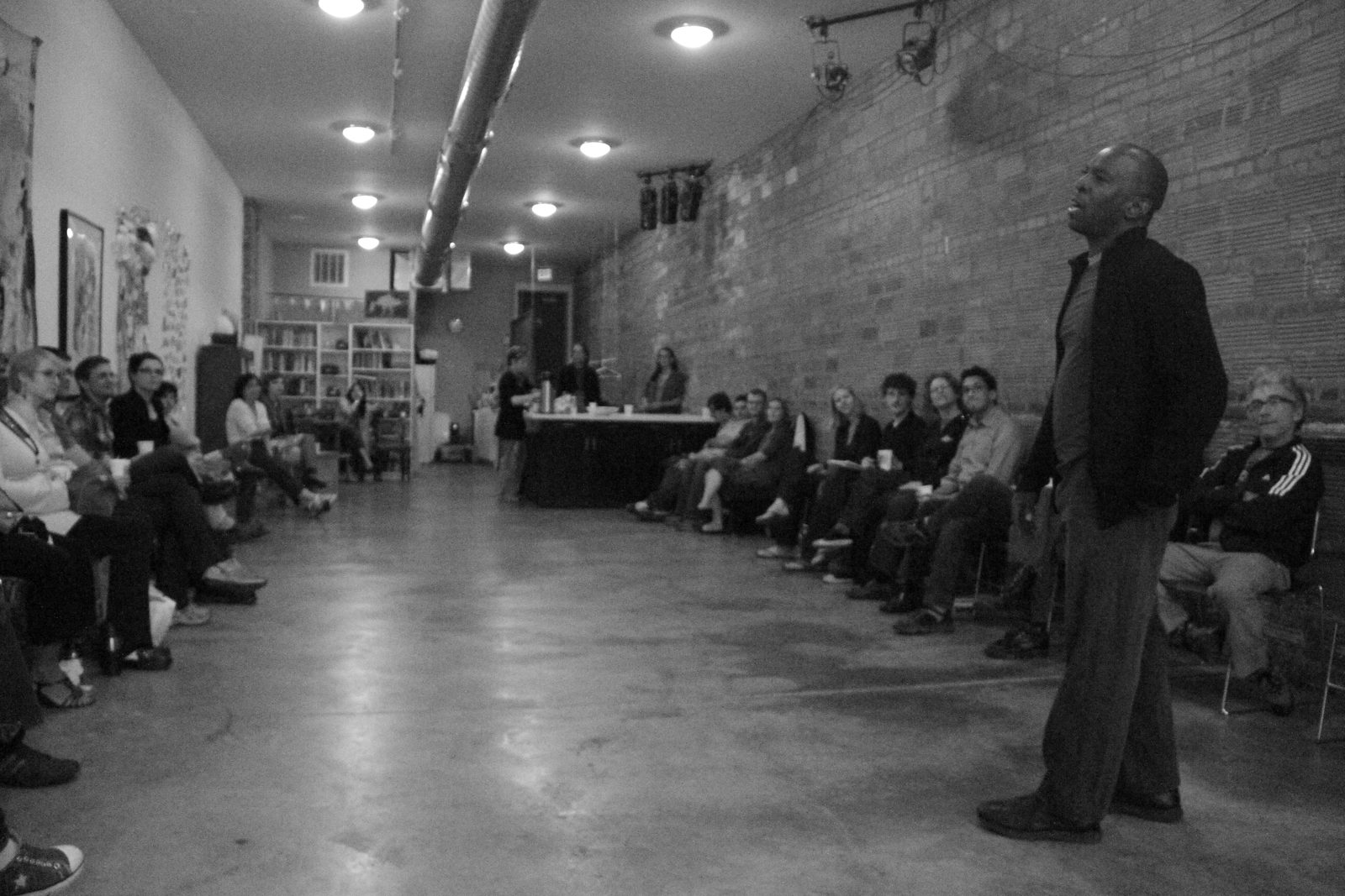Boris Willis standing in profile before the audience along the brick wall