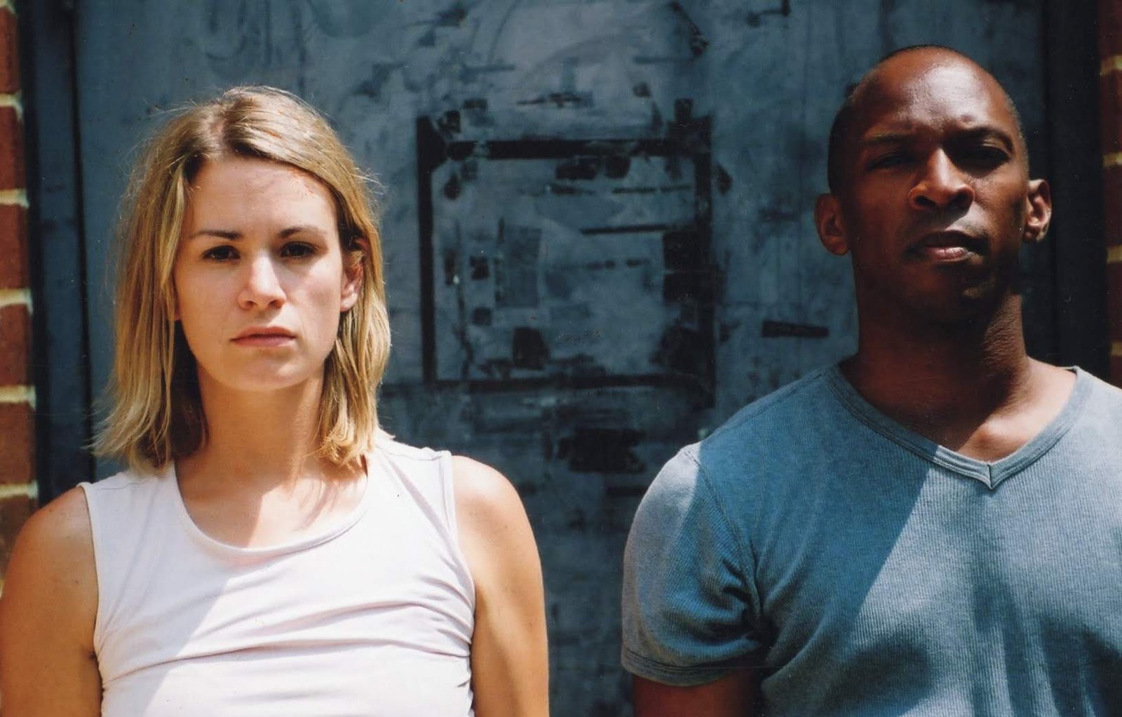 Boris Willis and Cynthia McLaughlin facing forward against an industrial wall in Enter Race